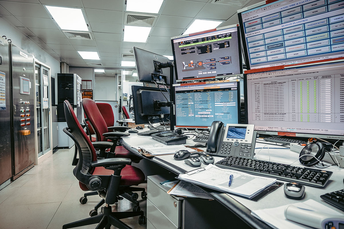 An empty process control room with operator chairs facing a bank of SCADA and alarm monitoring screens